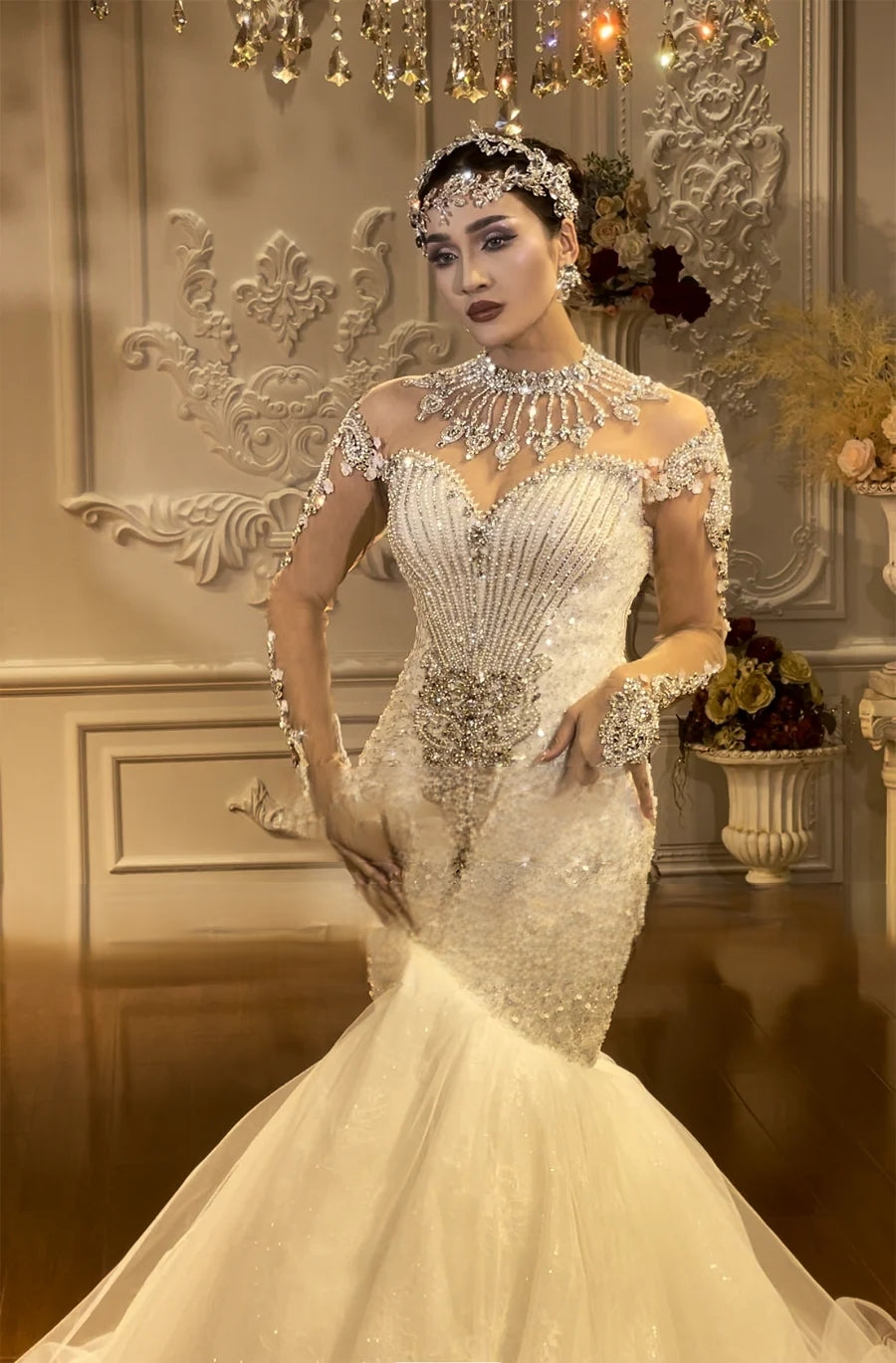 Three-quarter front angle of a long sleeve mermaid wedding dress showcasing heavy silver beadwork, crystalline detailing, and a shimmering fit-and-flare silhouette.