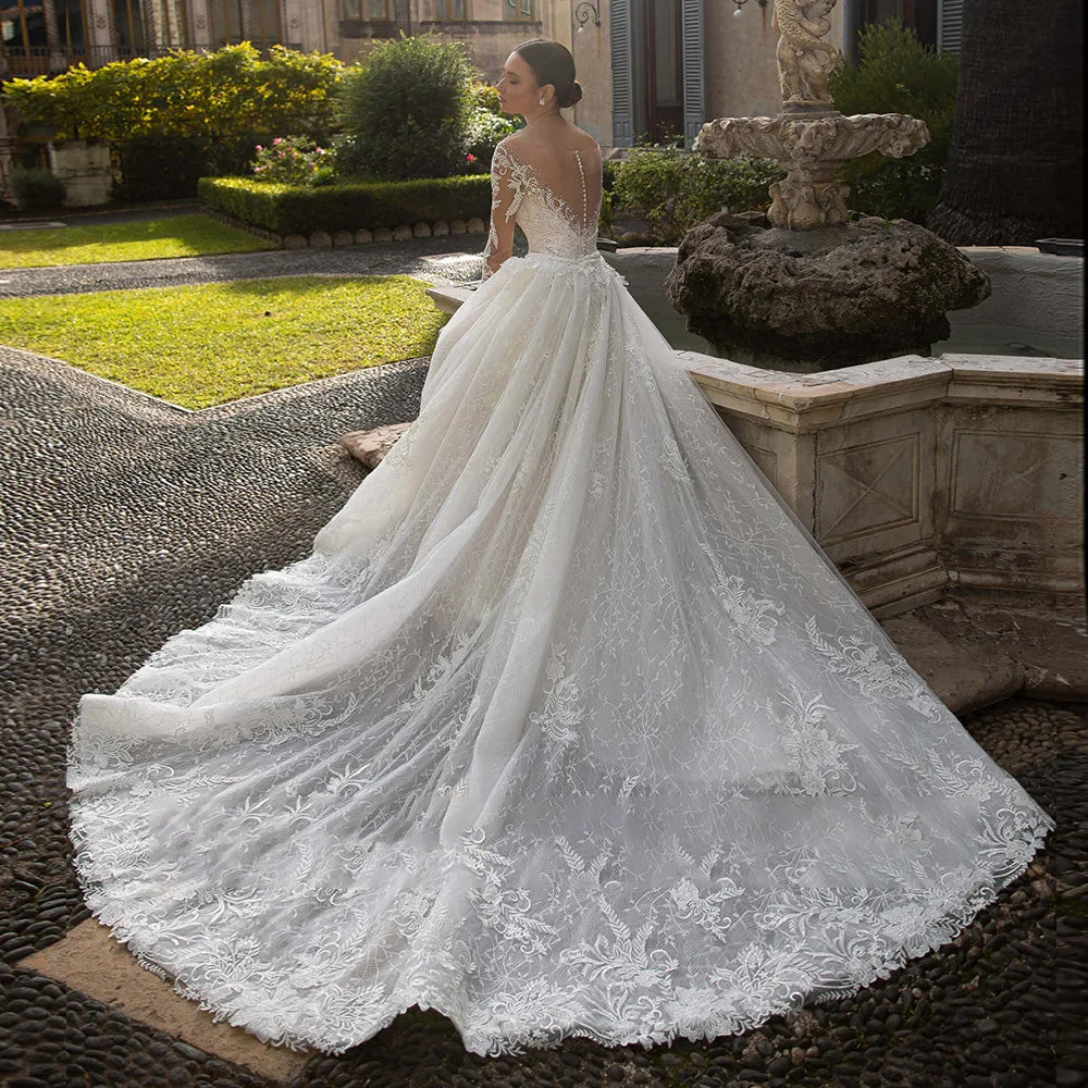Rear view of an elegant long-sleeve mermaid wedding dress, showcasing the intricate beaded back and the stunning detachable train attachment.