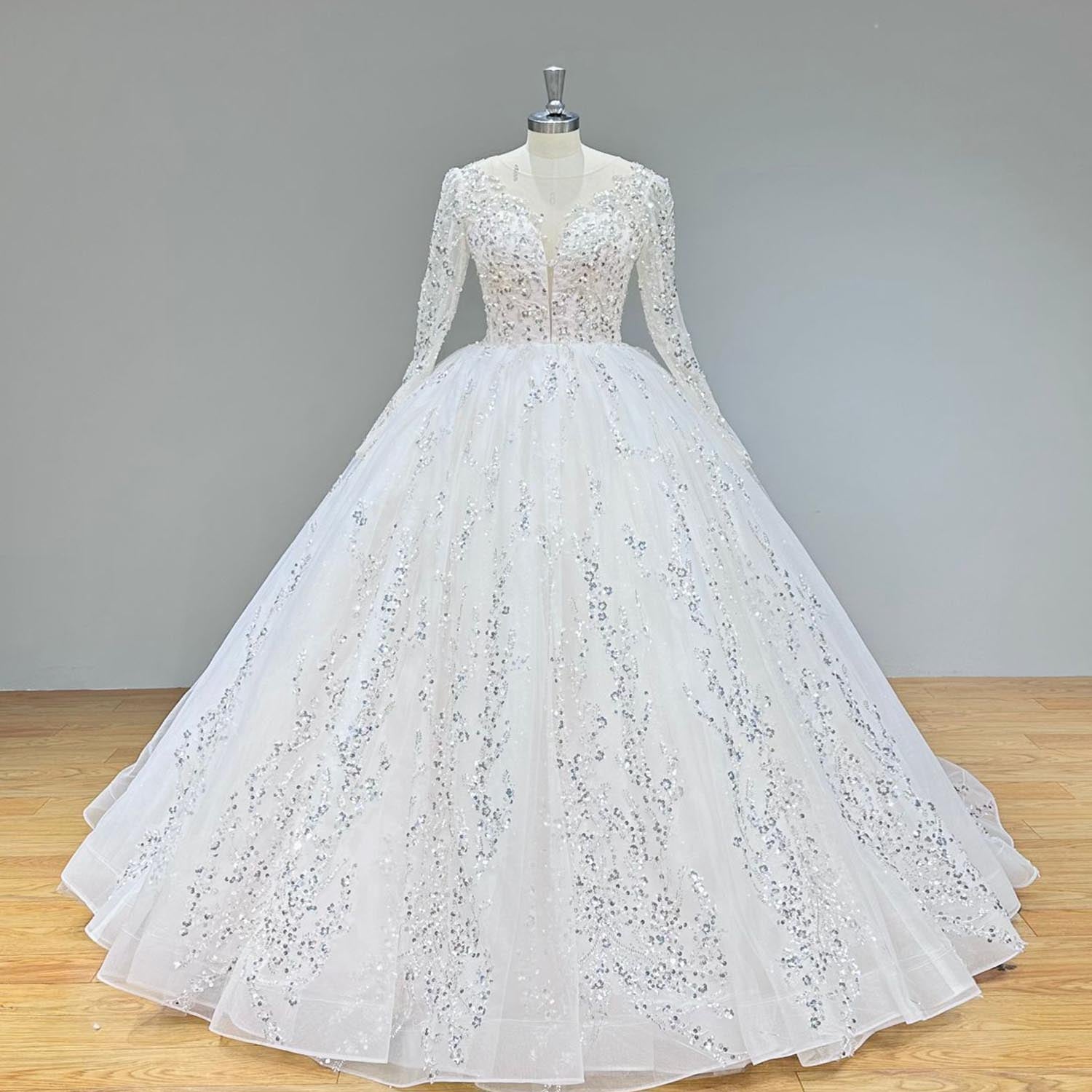 Front profile of an elegant long-sleeve wedding ball gown with intricate floral sequin embroidery on a display mannequin."