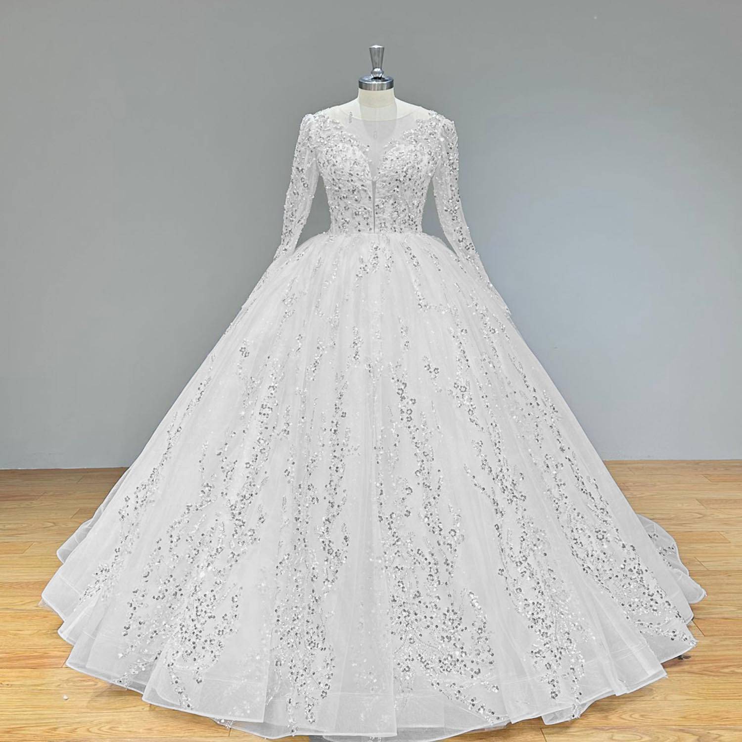 Full-length view of a classic long-sleeve ball gown bridal dress with sequin appliqué and a full skirt displayed on a mannequin.