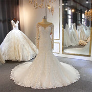Full-length front view of a long sleeve full lace mermaid wedding dress on a mannequin, featuring an elegant fit, sweetheart illusion neckline, and a sprawling floral lace train.