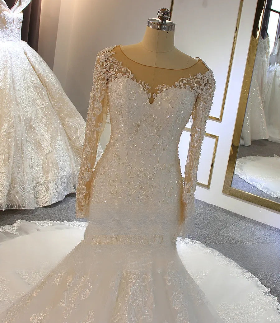 Close-up front view of a beaded lace wedding dress bodice, detailing the intricate floral patterns, long lace sleeves, and elegant sweetheart neckline under a sheer illusion top.