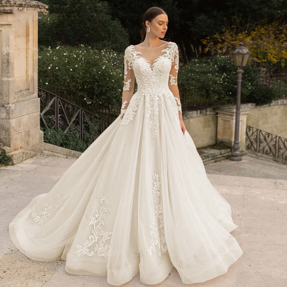 Elegant bride wearing a long sleeve lace A-line wedding dress with intricate beaded bodice and soft illusion details.