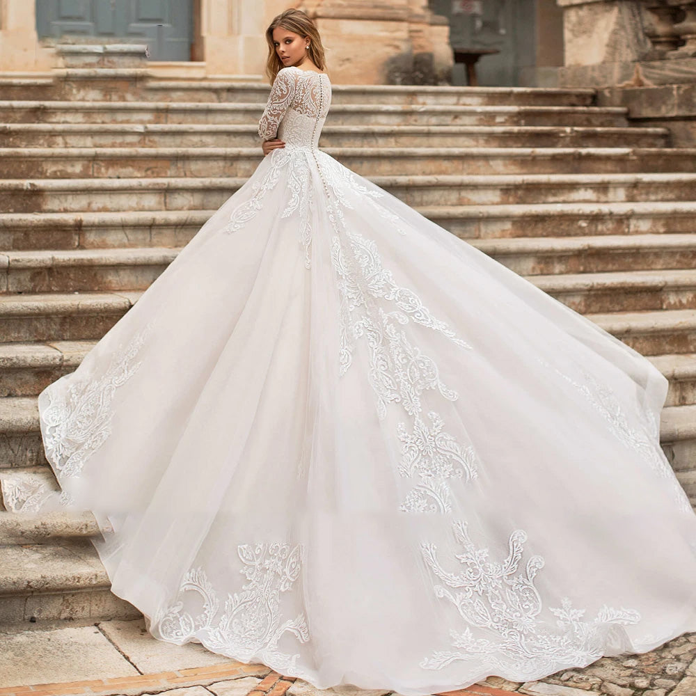 Back view of a stunning A-line bridal gown with a long lace-trimmed train and button-up back detail on stone stairs.