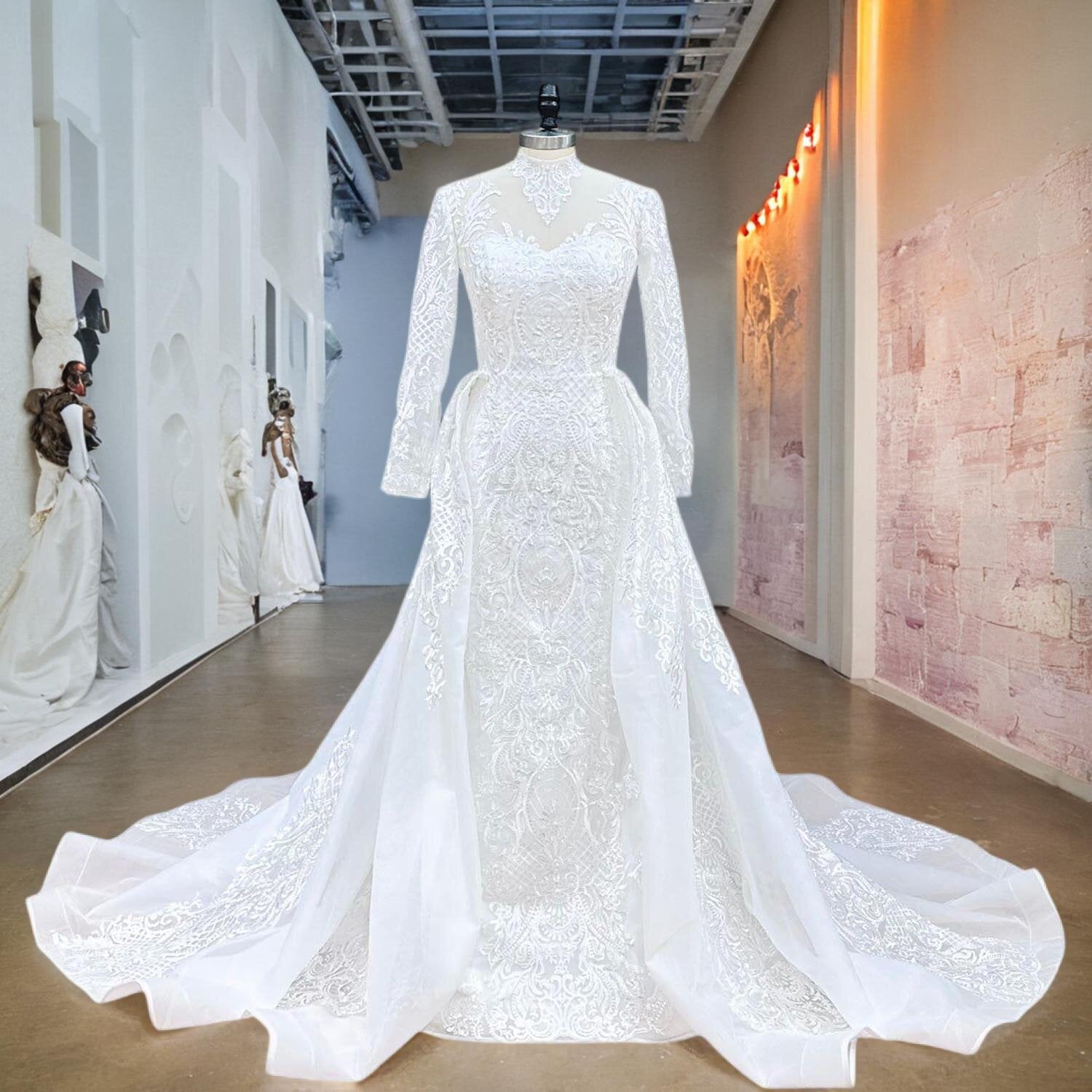 Front view of a luxury long-sleeve mermaid wedding dress with detachable train and hand-beaded floral lace appliqués on a mannequin.