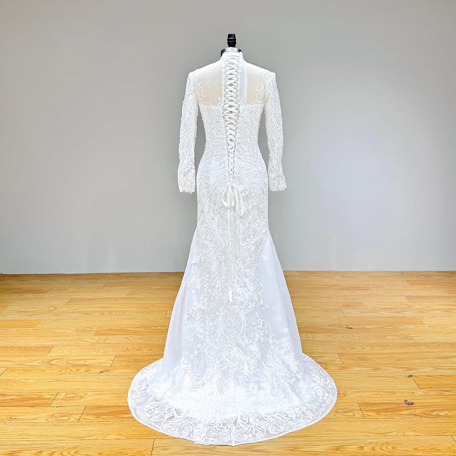 Full back view of a long-sleeve mermaid wedding dress with detachable train, showcasing the lace-up corset and intricate pearl detailing.