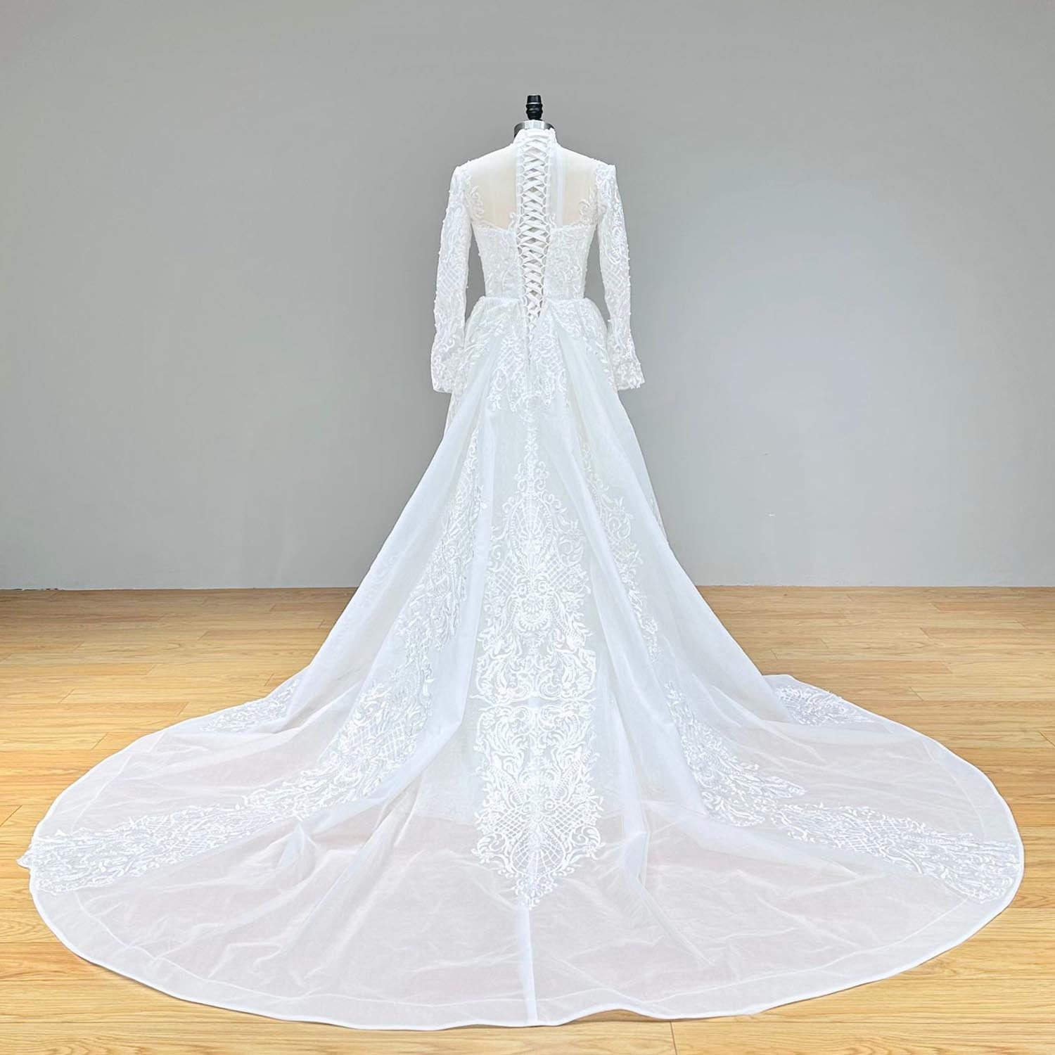 Back view of a long-sleeve lace mermaid wedding dress on a mannequin, highlighting the dramatic lace-embellished detachable train.