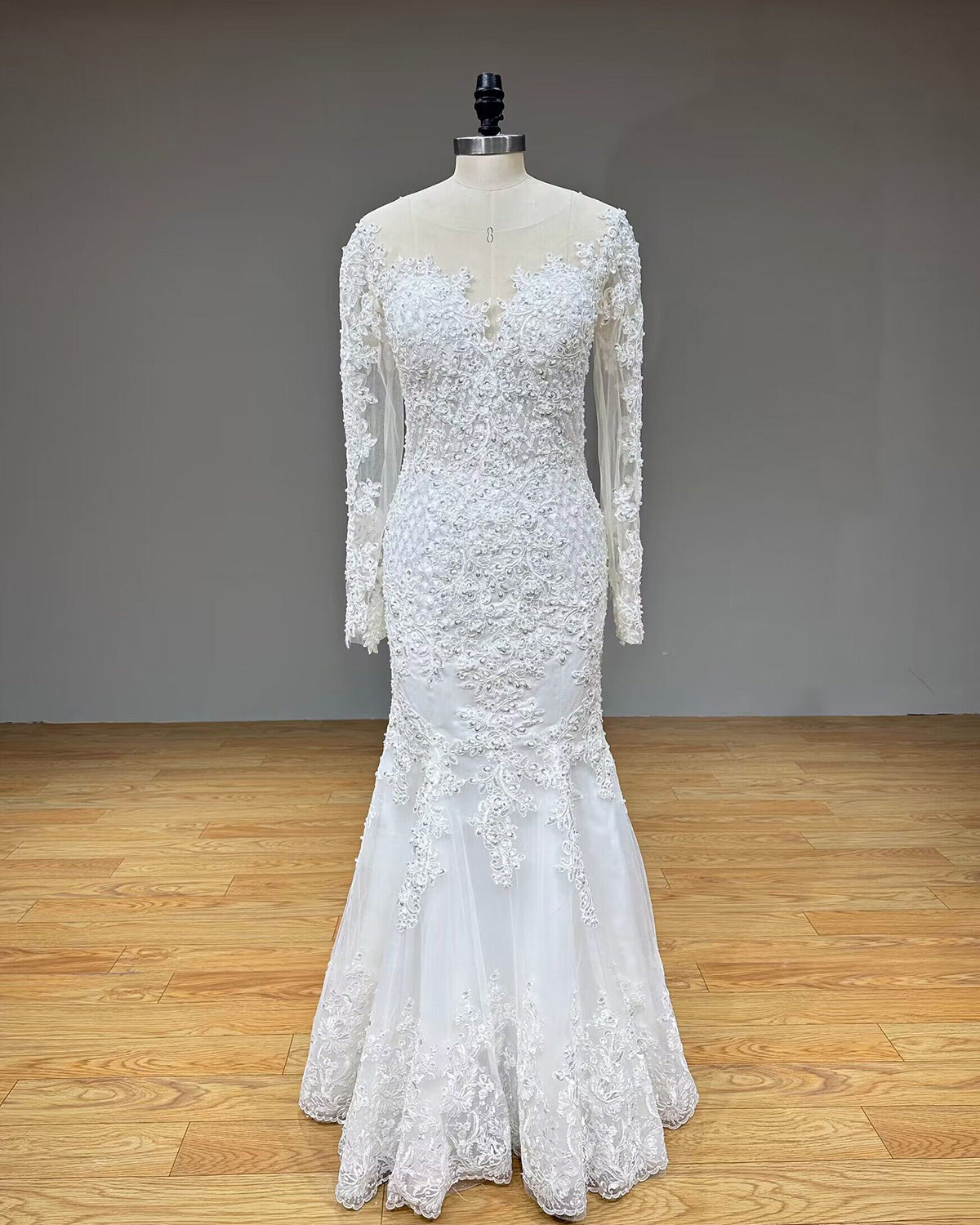 Full-length front view of an ivory long sleeve mermaid wedding dress without the train, showcasing the fitted trumpet silhouette and intricate lace embroidery on a mannequin.
