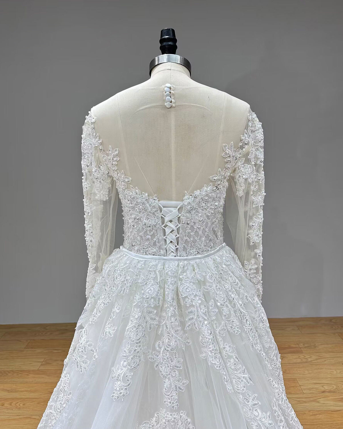 Back view of the luxury wedding dress on a mannequin with the voluminous detachable tulle overskirt attached at the natural waistline.