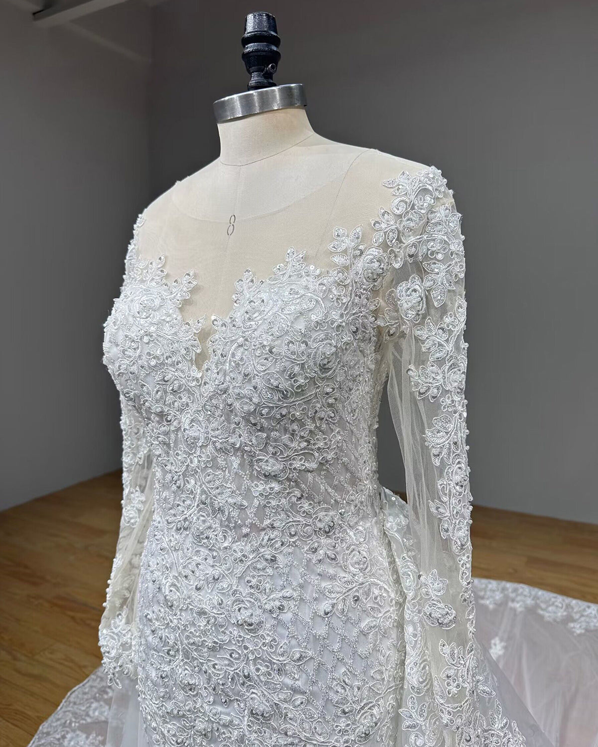 Angled side profile close-up of the front bodice, emphasizing the detailed lattice sequin patterns, 3D lace appliques, and fitted sheer long sleeves.
