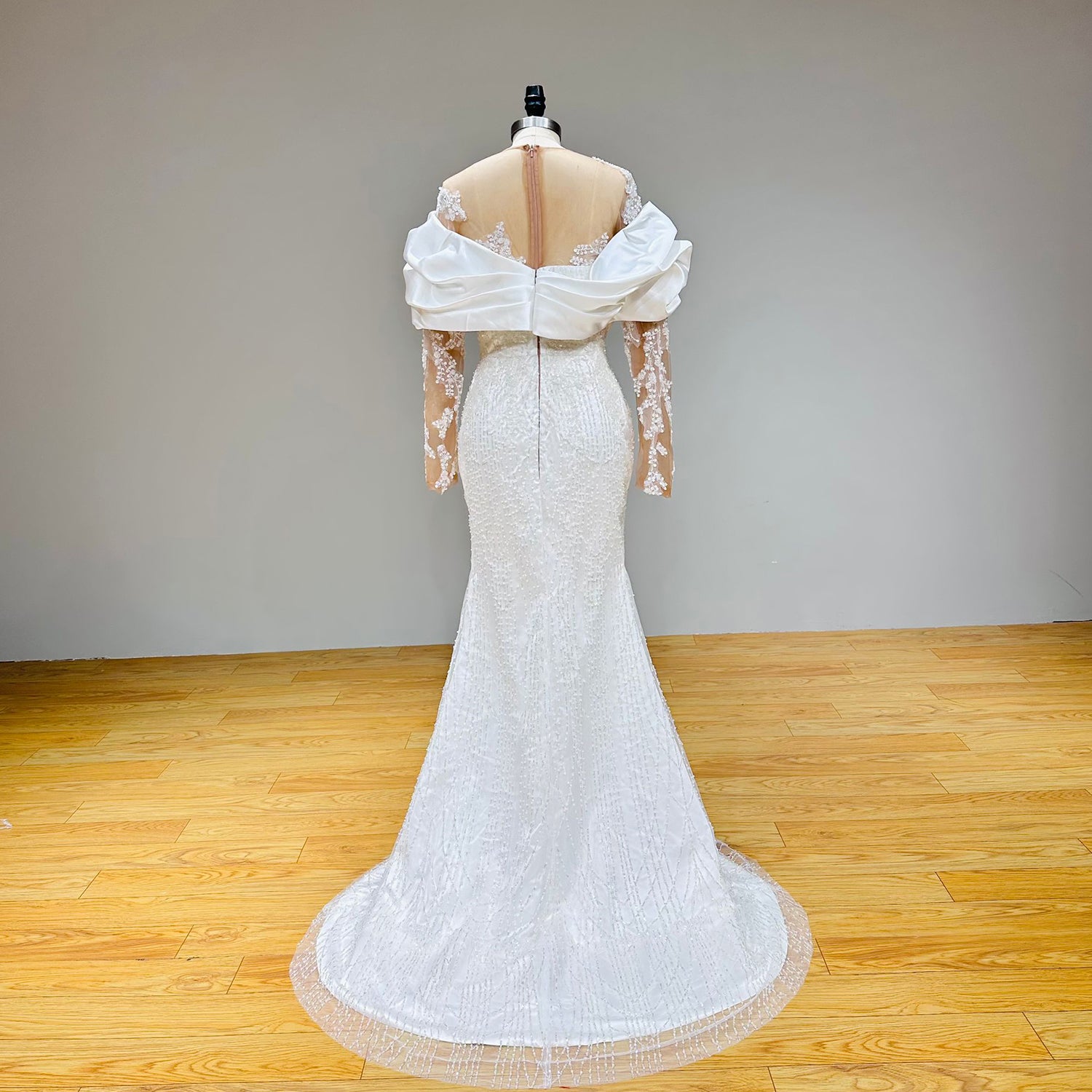 Back view of the inner column bridal gown highlighting the continuous vertical lines of glittering beadwork trailing down to a subtle pool train.