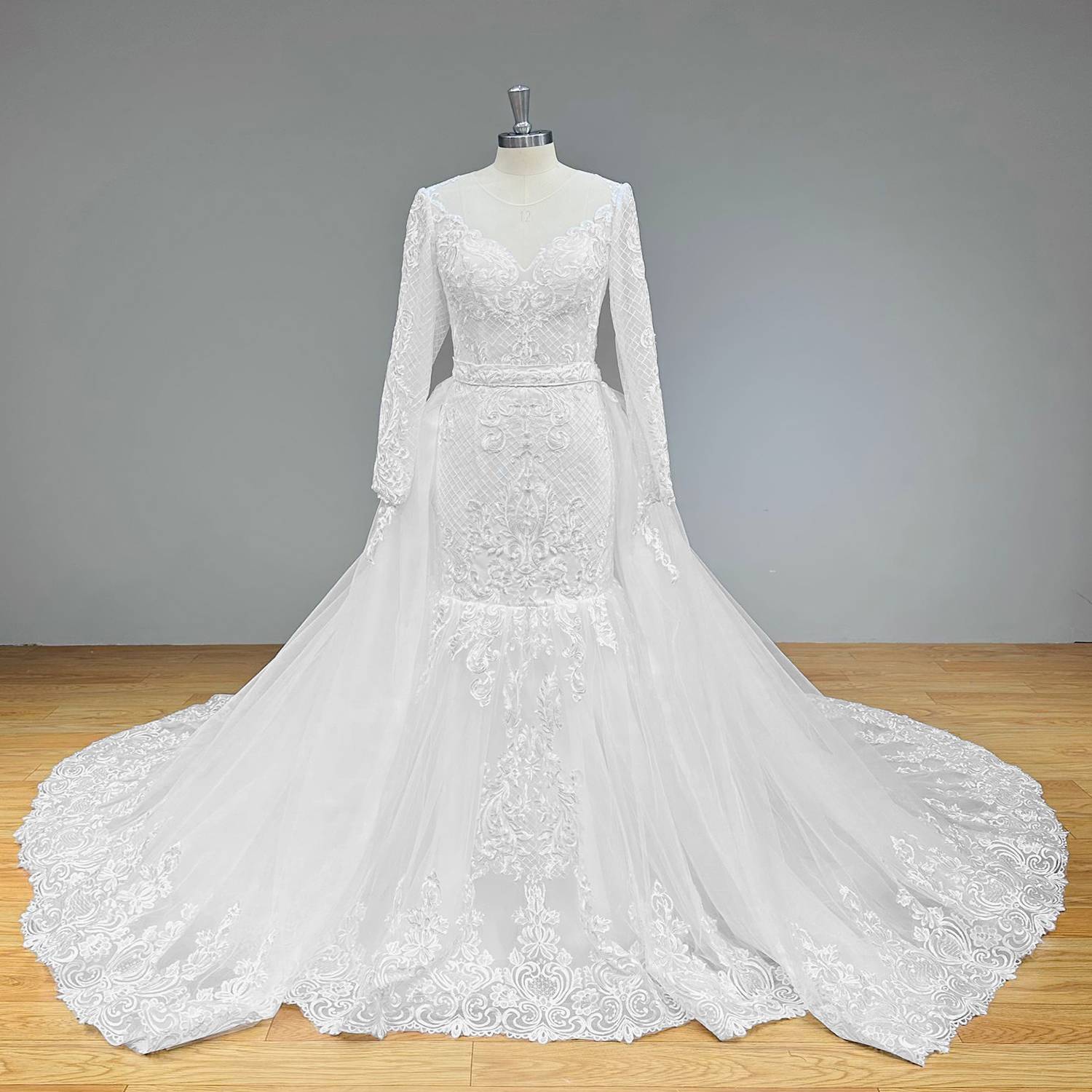 Full-length still highlighting the intricate silver-threaded lace hem and voluminous flare of a trumpet-style bridal gown with a matching lace-trimmed detachable train.