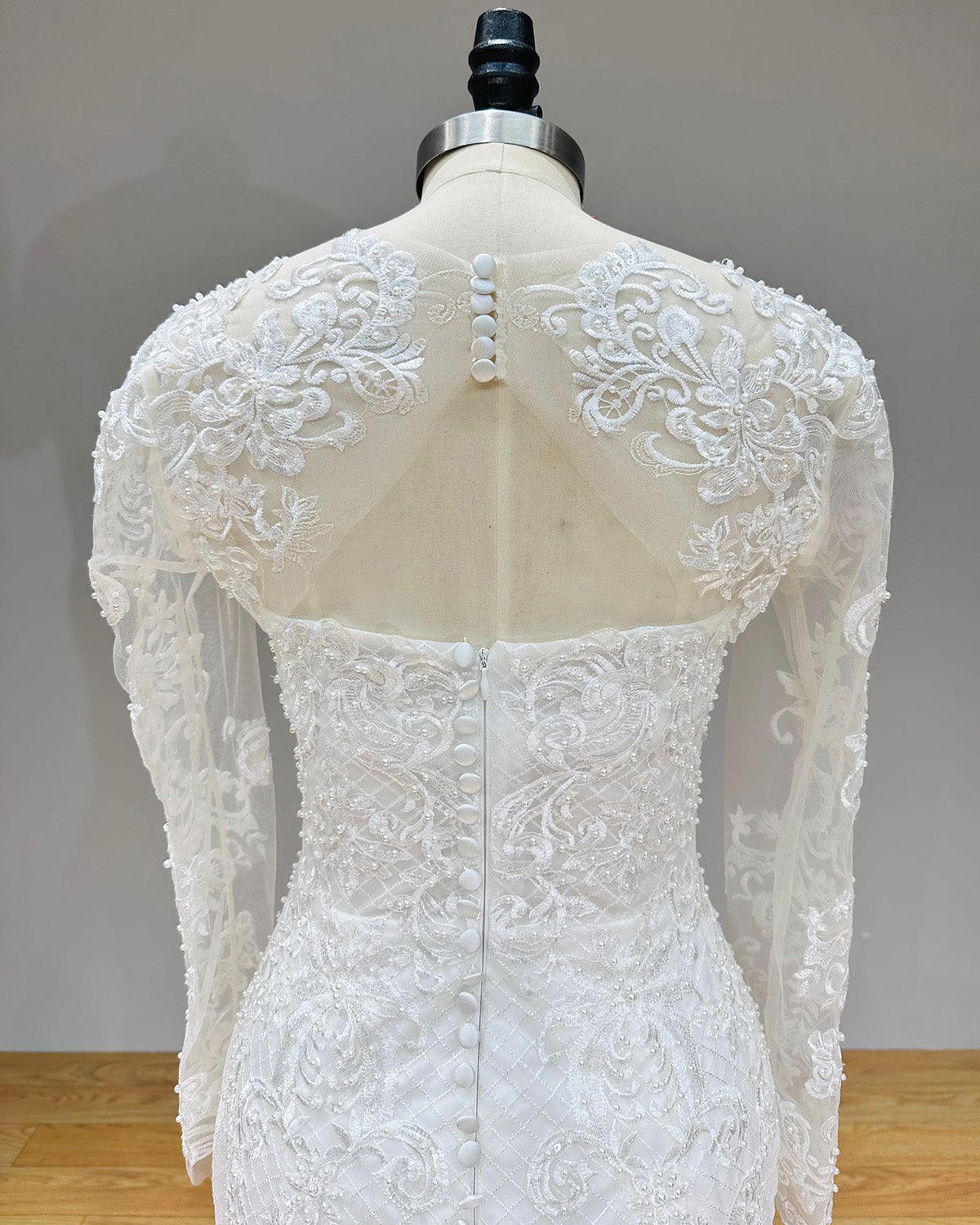 Close-up back view of the bridal gown bodice highlighting the button-up illusion lace jacket, open keyhole detail, and delicate pearl beadwork.