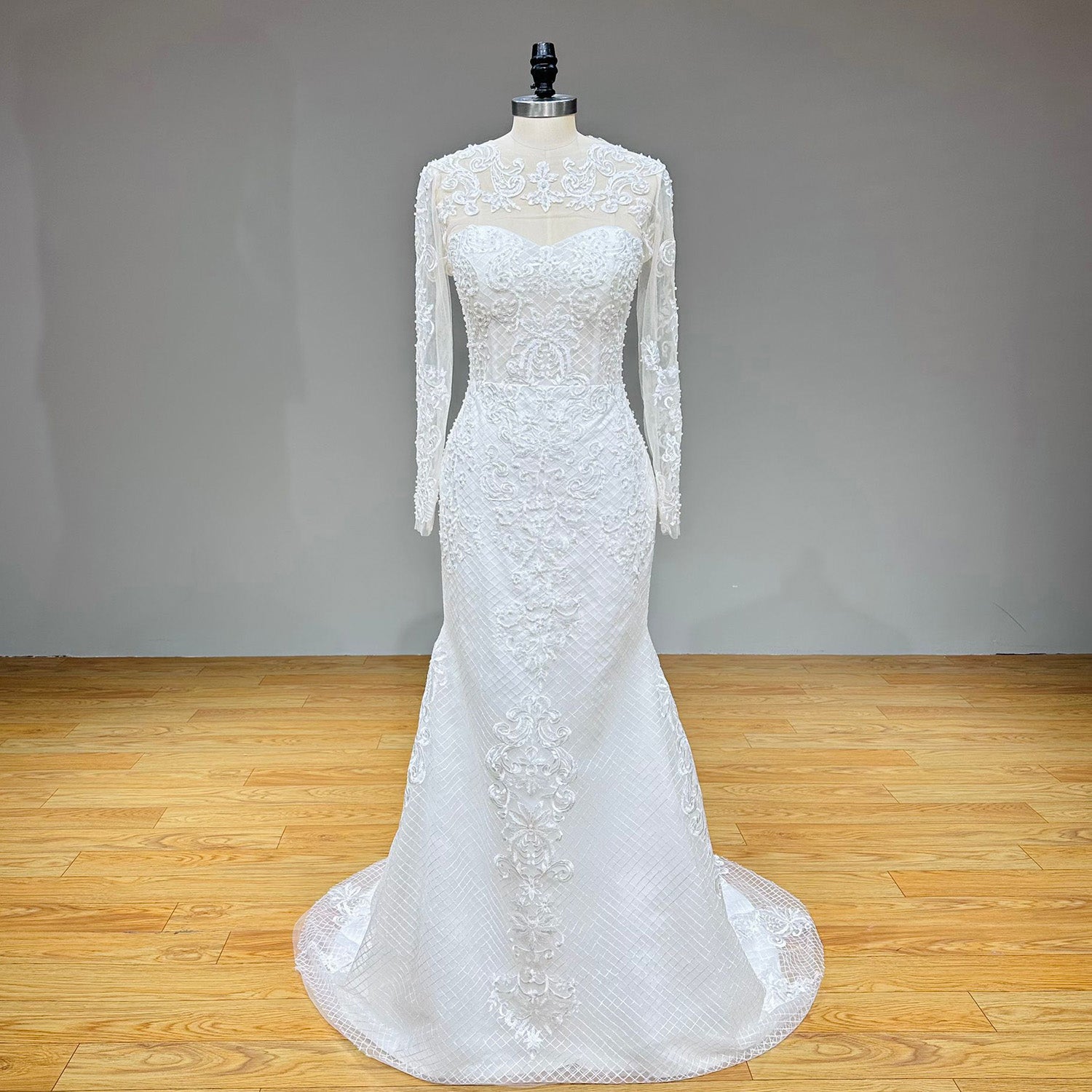 Complete front product shot of the long sleeve mermaid wedding gown with a removable sheer high-neck lace jacket on a studio mannequin.
