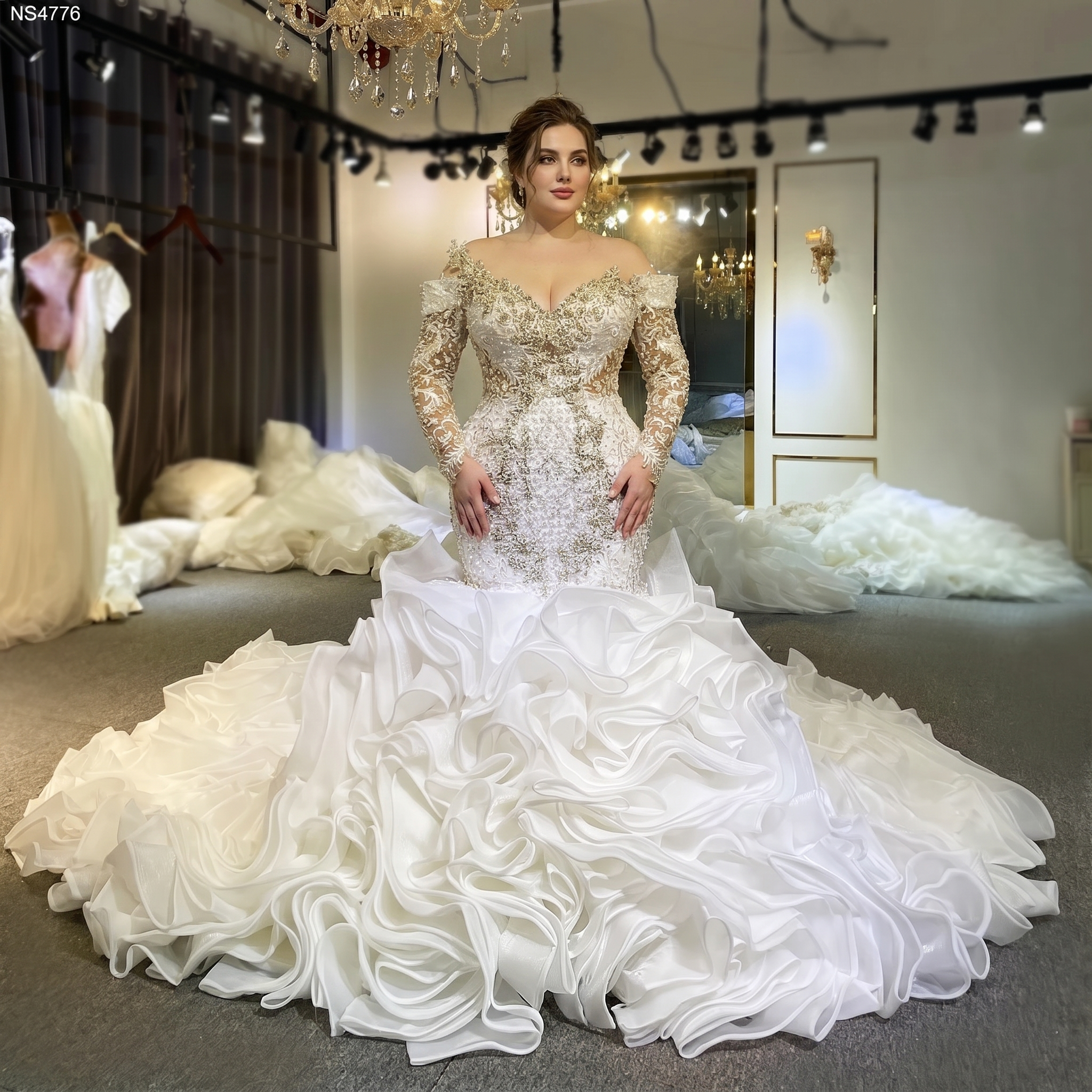 A boutique display of an elegant mermaid-style bridal gown featuring long sleeves, intricate gold and crystal beadwork, and a voluminous ruffled train.