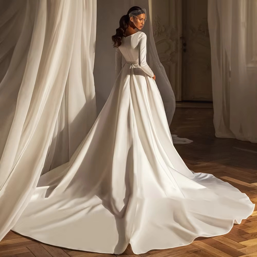 Back view of an elegant A-line satin bridal gown showing a classic crew neckline, long tailored sleeves, and an expansive cathedral-length.