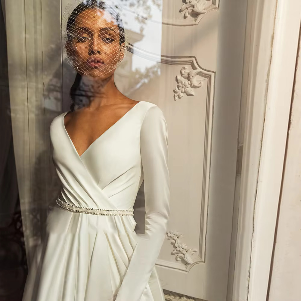Artistic bridal portrait featuring a sheer birdcage veil and the draped V-neck bodice of a luxury silk-satin wedding gown.