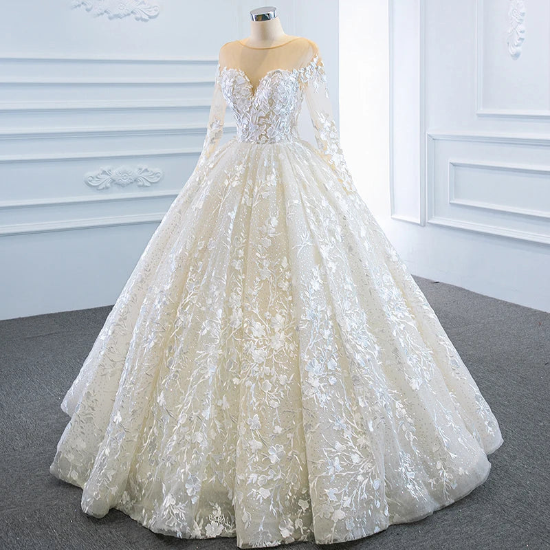 Full-length side angle of an elegant A-line bridal gown, emphasizing the dramatic volume of the sparkly lace skirt and transparent long sleeves.