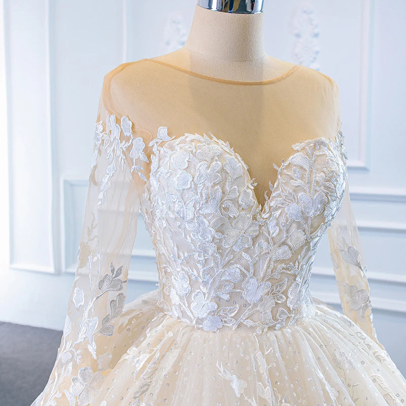 Close-up front view of a bridal gown bodice, showcasing the transparent illusion neckline, sweetheart plunge insert, and delicate floral lace detailing.