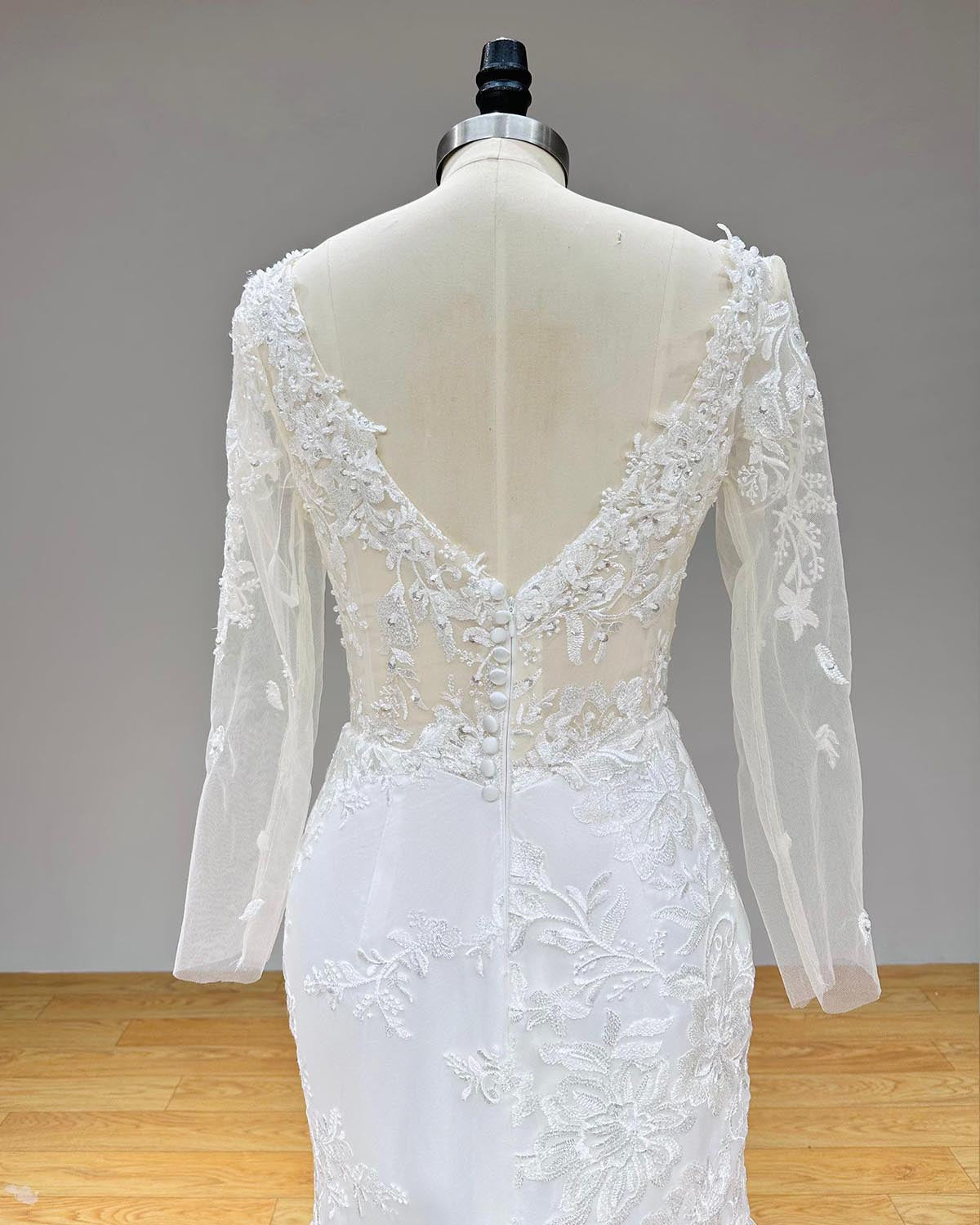 Close-up back view of the sheer illusion V-back on a lace mermaid wedding dress highlighting delicate floral embroidery and covered buttons.