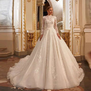 A bride wearing a luxury A-line long-sleeve wedding dress with a high neck, intricate lace applique, and a full ball gown skirt.