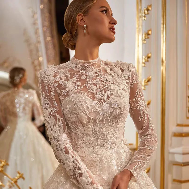 A detailed close-up of a high-neck long-sleeve bridal gown bodice, highlighting exquisite floral lace applique and intricate embroidery.