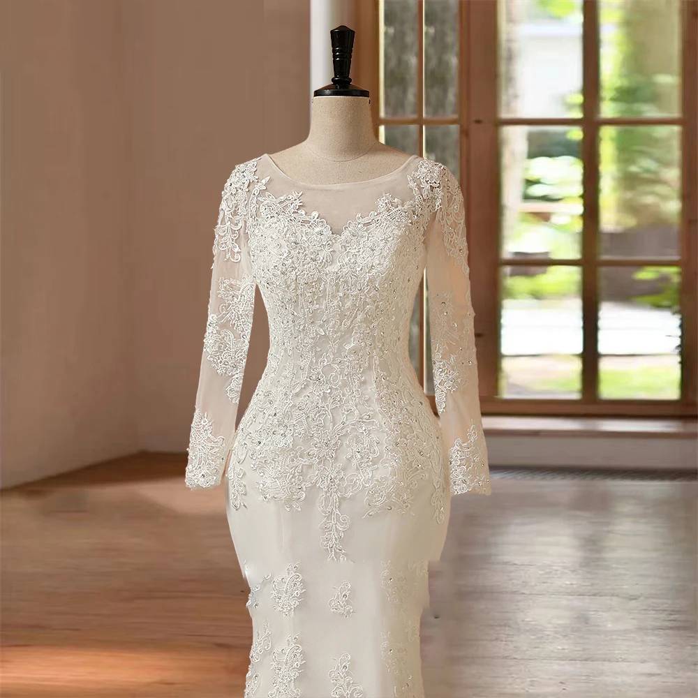Close-up bodice detail of a long sleeve mermaid bride gown, emphasizing the sparkling beadwork, sheer illusion neckline, and heavy floral lace embroidery on the fitted sleeves.