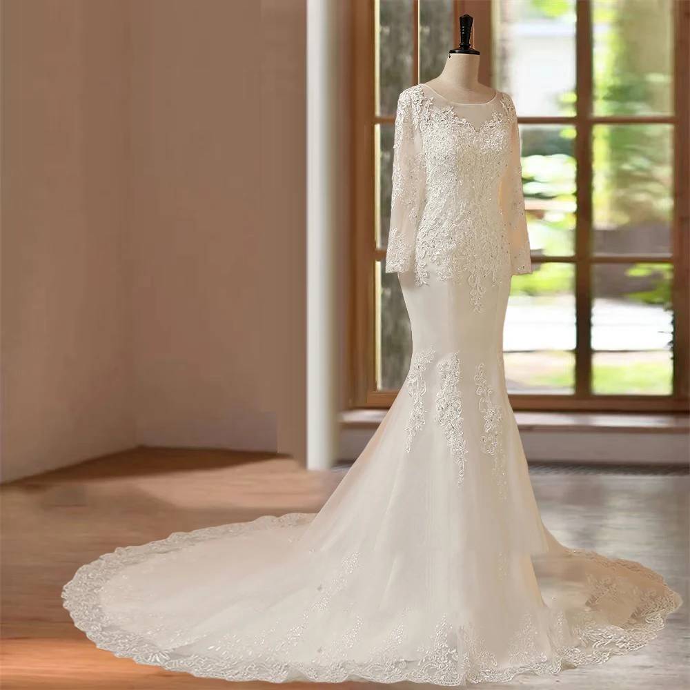 Three-quarter side angle of an elegant fit-and-flare long sleeve bridal gown on a mannequin, showcasing the graceful transition from the heavily appliquéd bodice to the flared mermaid skirt.
