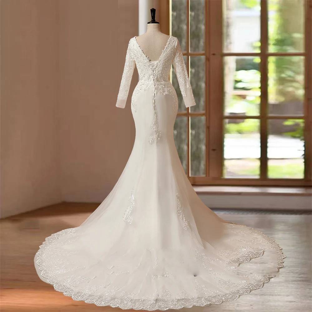 Back view of an elegant long sleeve mermaid bridal gown on a mannequin, showcasing a sheer illusion lace back, delicate button detailing, and a sweeping lace-trimmed train.