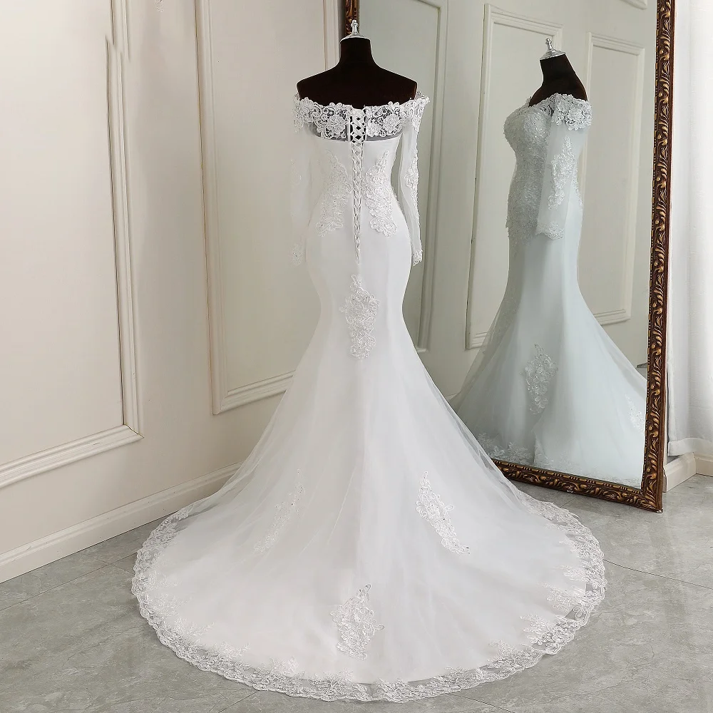 A full-length rear view of an elegant off-the-shoulder, long-sleeve mermaid bridal gown on a mannequin, showcasing the lace-up back and flowing train.
