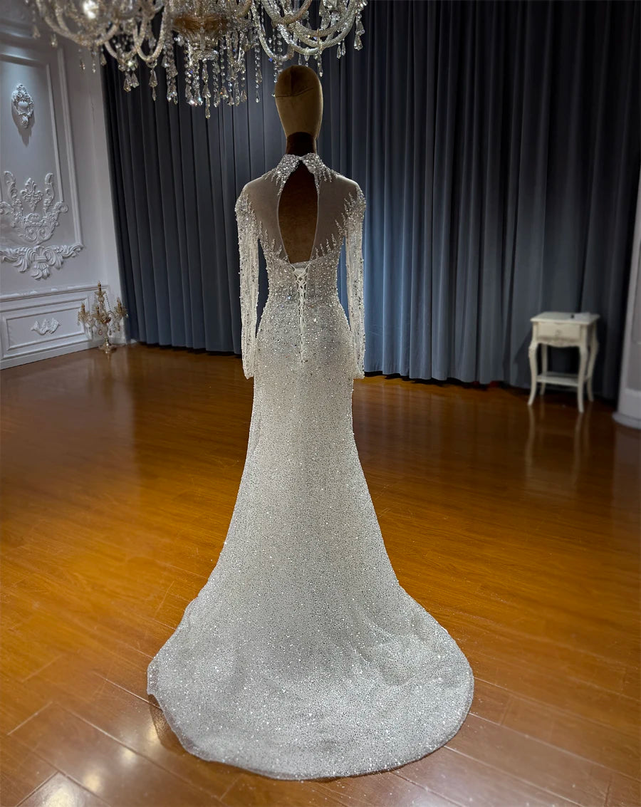 The rear view of the beaded mermaid wedding gown on a mannequin, showcasing a sophisticated teardrop keyhole back design and a traditional lace-up corset closure.