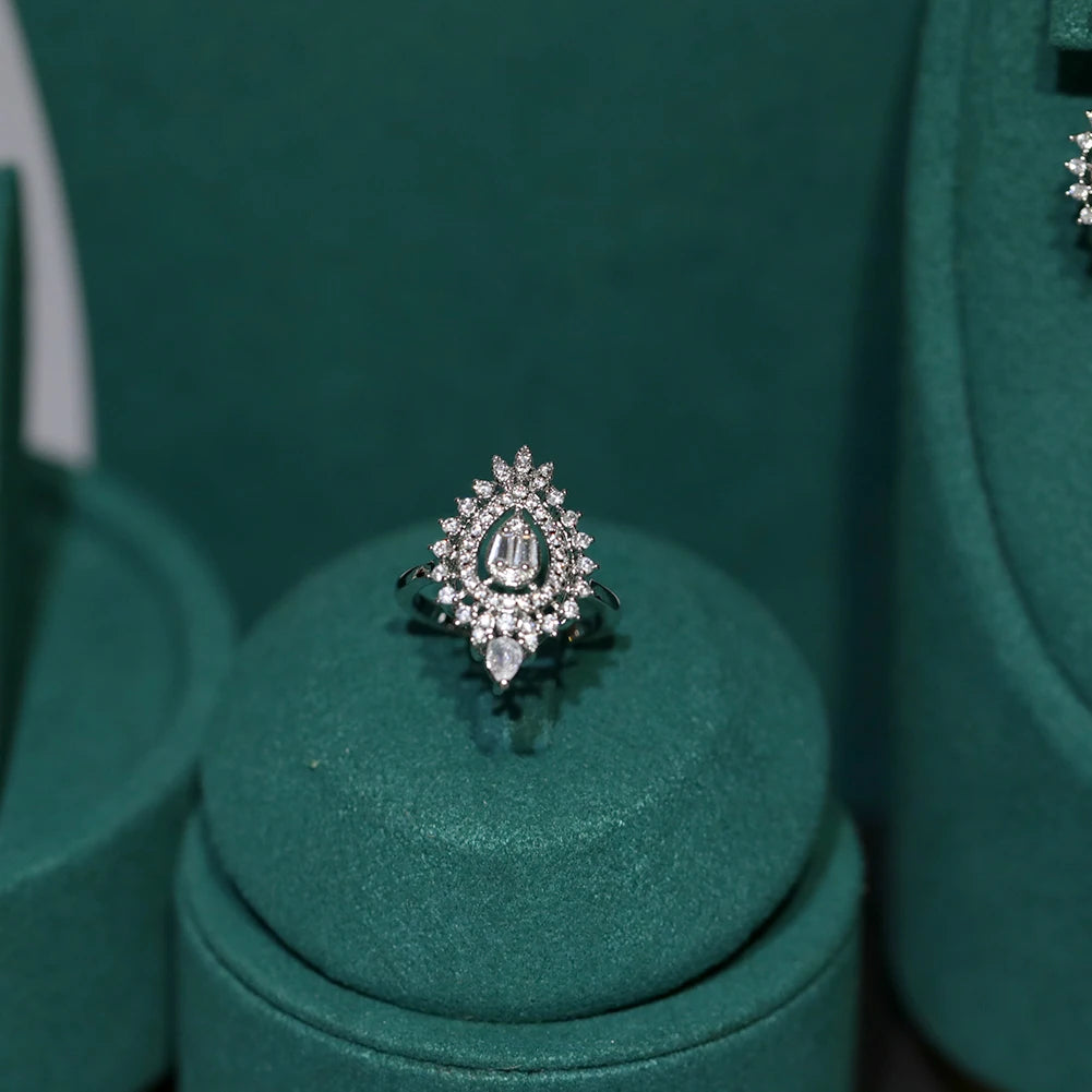 Elegant cubic zirconia bridal ring with a teardrop centerpiece stone displayed on a green velvet stand.
