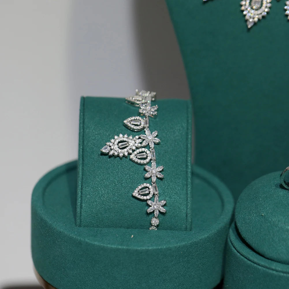 Detailed view of a matching silver cubic zirconia bridal flower and leaf design bracelet on a green velvet display mount.