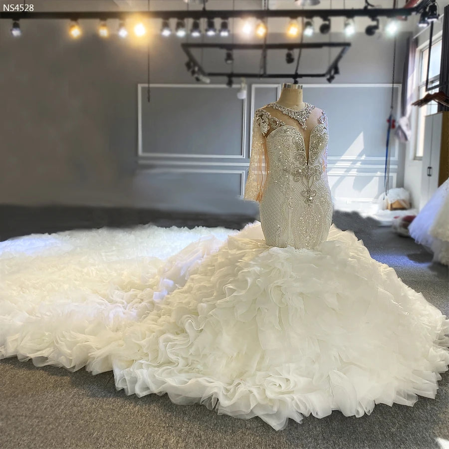 Full frontal pose of a bride in a shimmering 2-in-1 mermaid bridal dress, highlighting the royal silhouette and the dramatic volume of the ruffled African bridal style.
