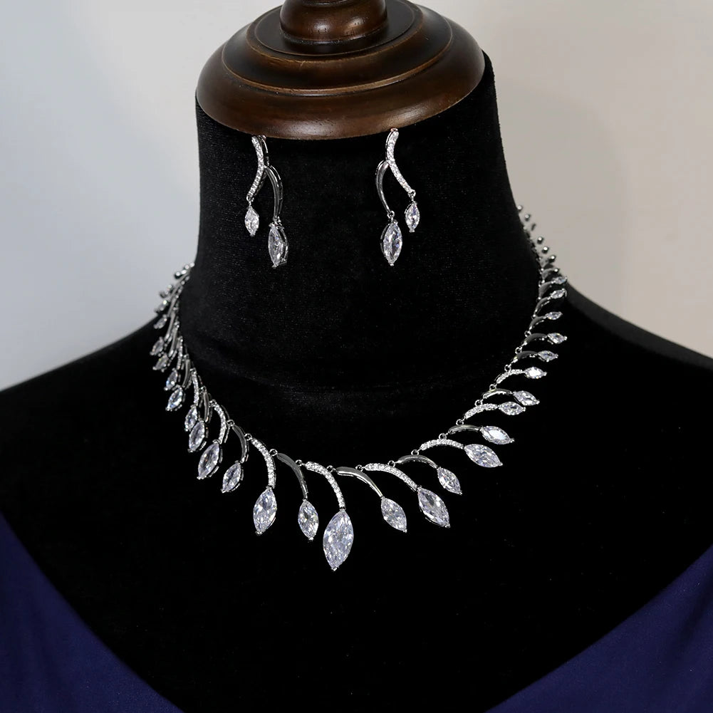 Front profile view of a silver round necklace and matching dropdown earrings set displayed on a black velvet jewelry bust.