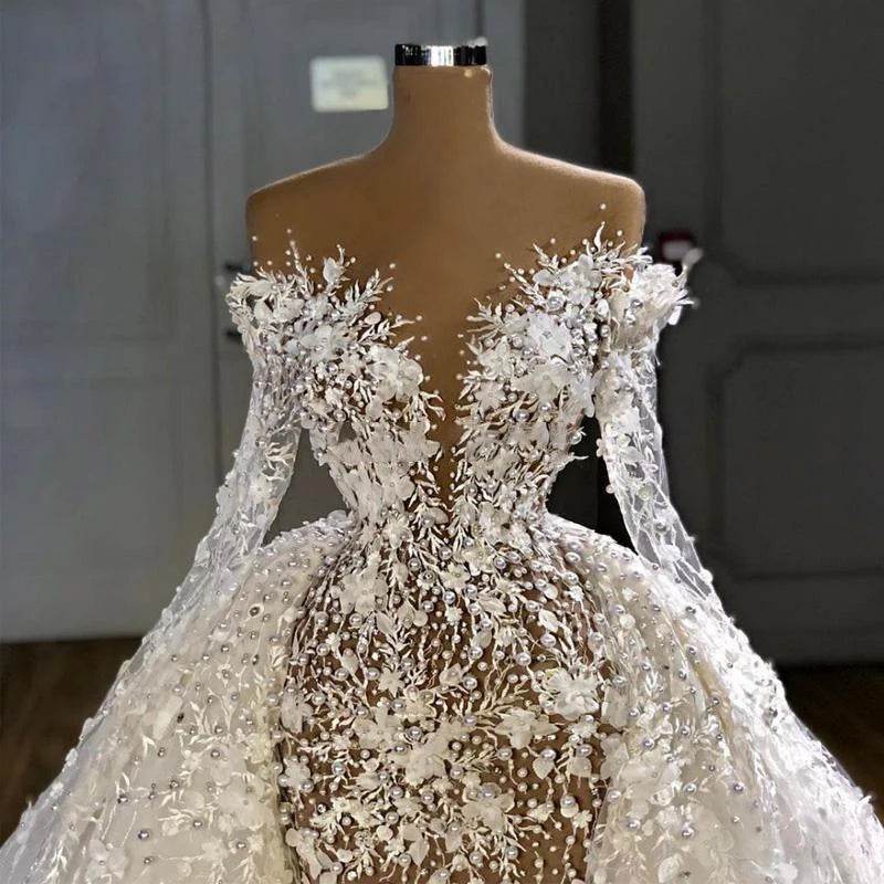 Detailed macro view of a luxury Arab bridal bodice emphasizing the plunging illusion V-neckline, intricate 3D lace flower clusters, and hand-stitched shimmering pearls.