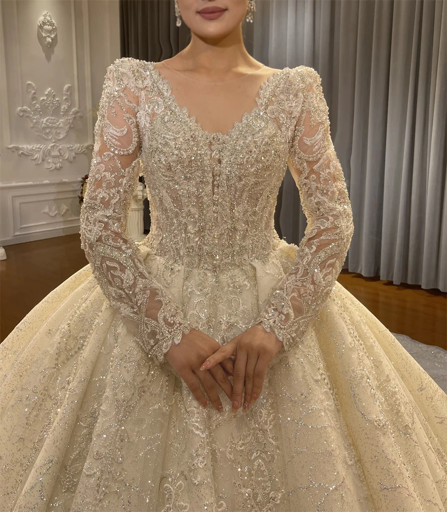 Close-up detail of the hand-beaded V-neck bodice and long lace sleeves of a luxury bridal gown, highlighting the premium craftsmanship and reflective crystals.