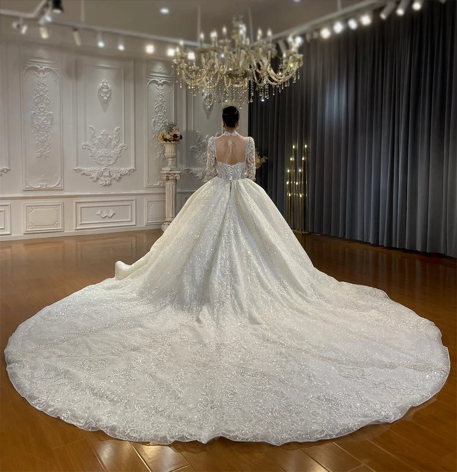 Rear view of the luxury wedding dress displaying an elegant open back design and an expansive, shimmering cathedral-length train covered in sequins.