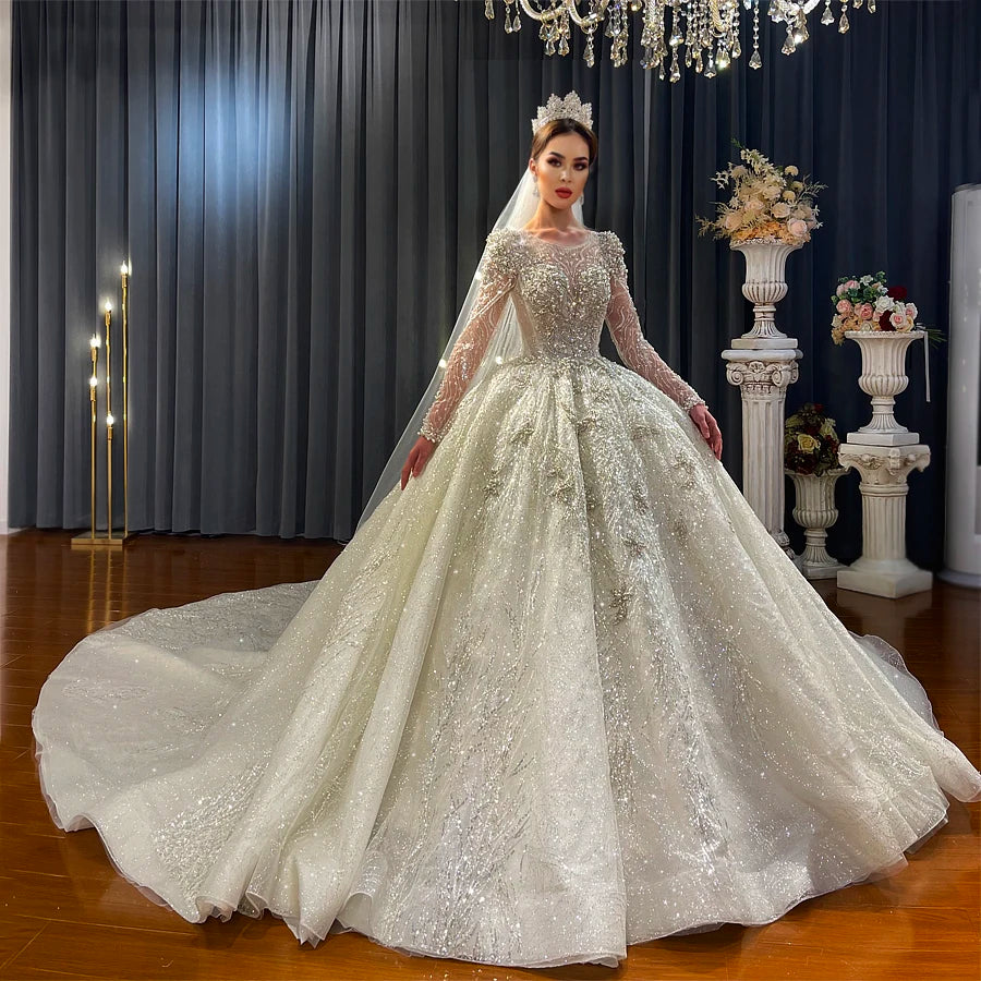 Glamorous long-sleeve beaded bridal gown with a full sparkly skirt and traditional bridal veil, emphasizing a high-fashion, modern silhouette for luxury weddings.