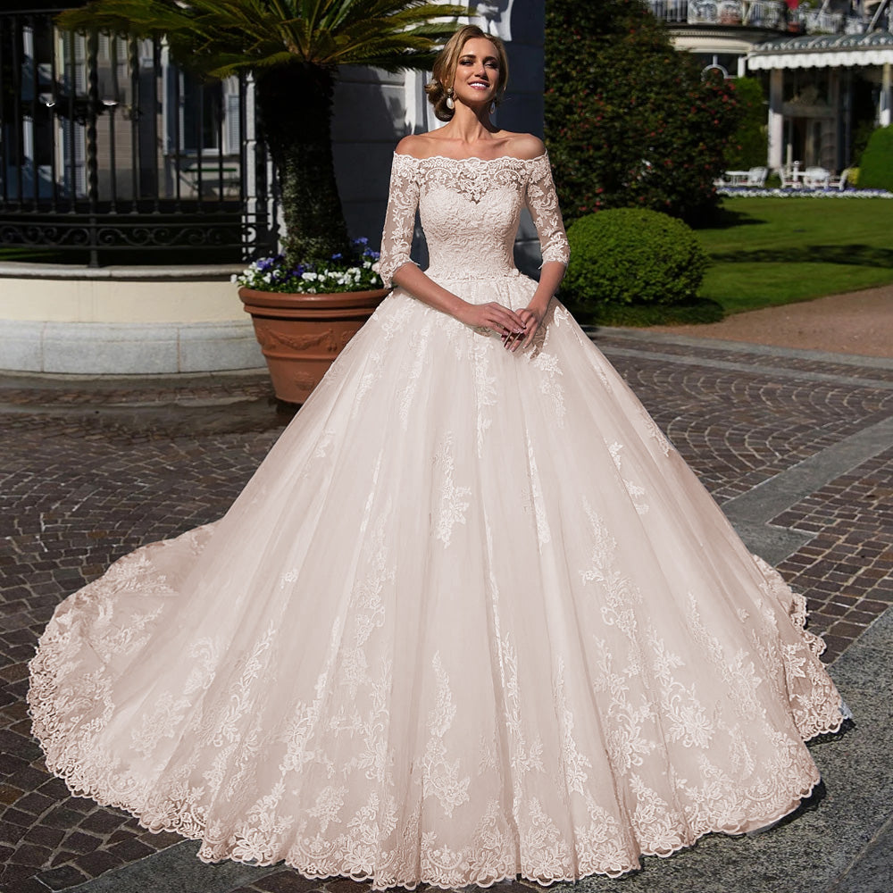 Close-up, full-length view of a luxury boat neck A-line bridal gown, highlighting the intricate appliques and elegant silhouette.