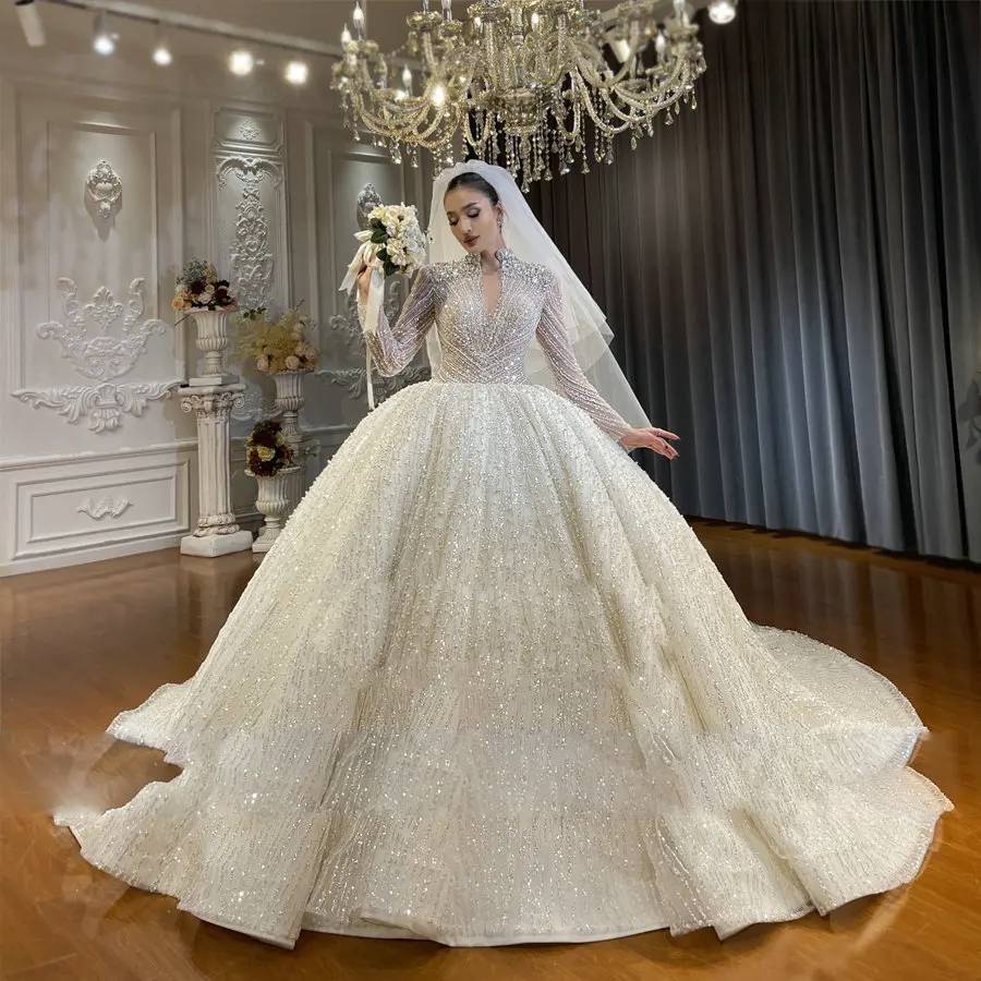 Side profile of an elegant bridal ball gown highlighting the grand volume of the shimmering skirt and the majestic silhouette under a crystal chandelier.
