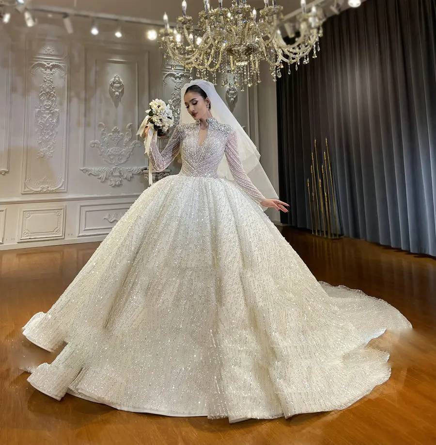 Professional showroom display of a heavy beaded bridal ball gown with long sleeves, showcasing a royal princess silhouette and high-end craftsmanship.