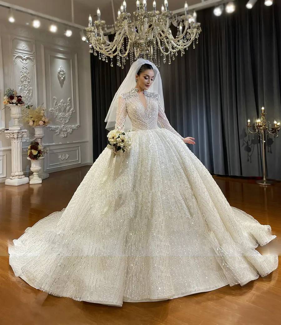 Side view of a luxury long-sleeve wedding dress on a mannequin, highlighting the wide-sweep shimmering skirt and the extraordinary detail of the bridal train.