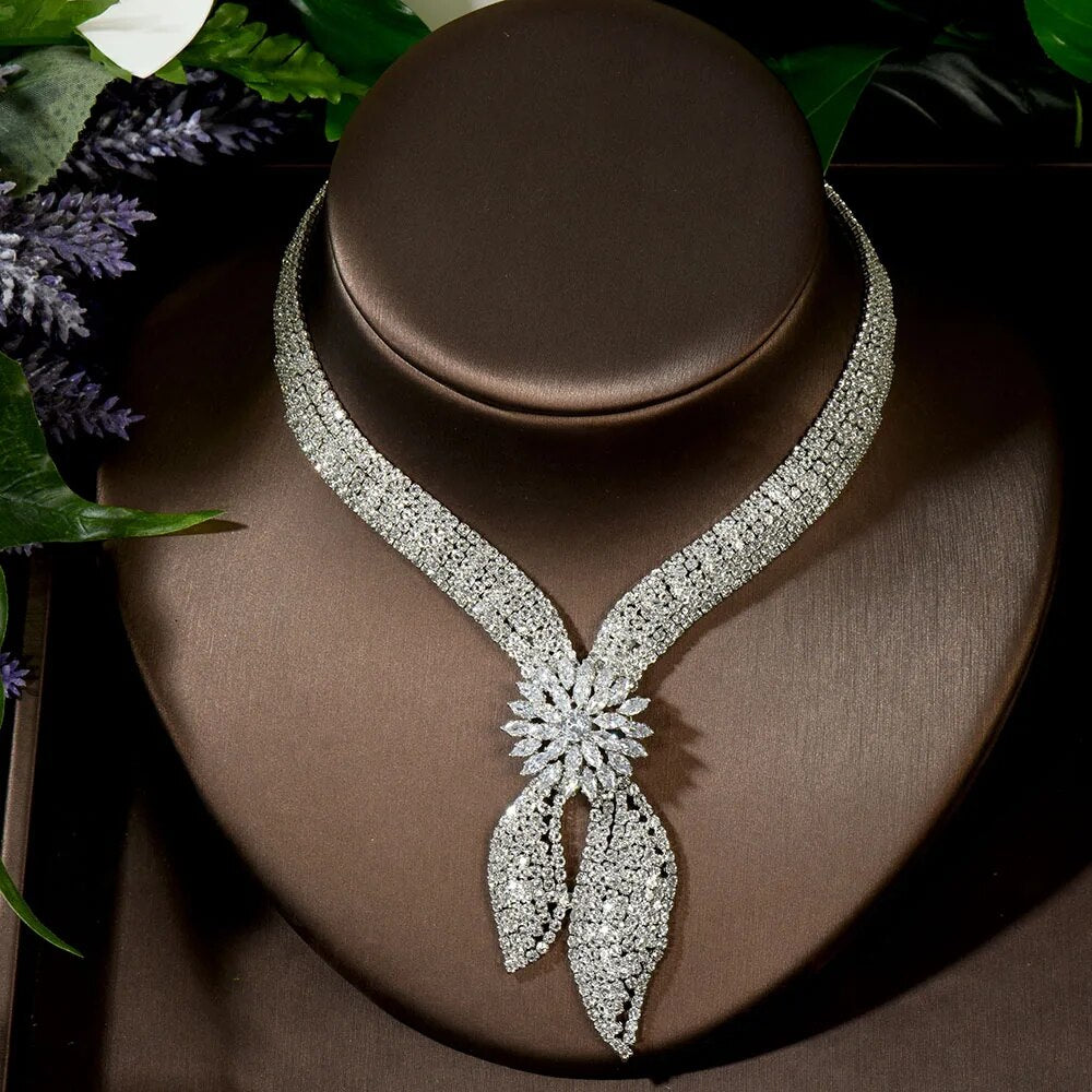 Front portrait of the multi-row clear crystal bridal collar necklace with a signature starburst flower drop centerpiece on a brown display bust.