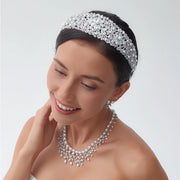 Close-up portrait of a smiling model wearing a luxury bridal pearl headband designed with a thick glamour crystal tiara cluster pattern.