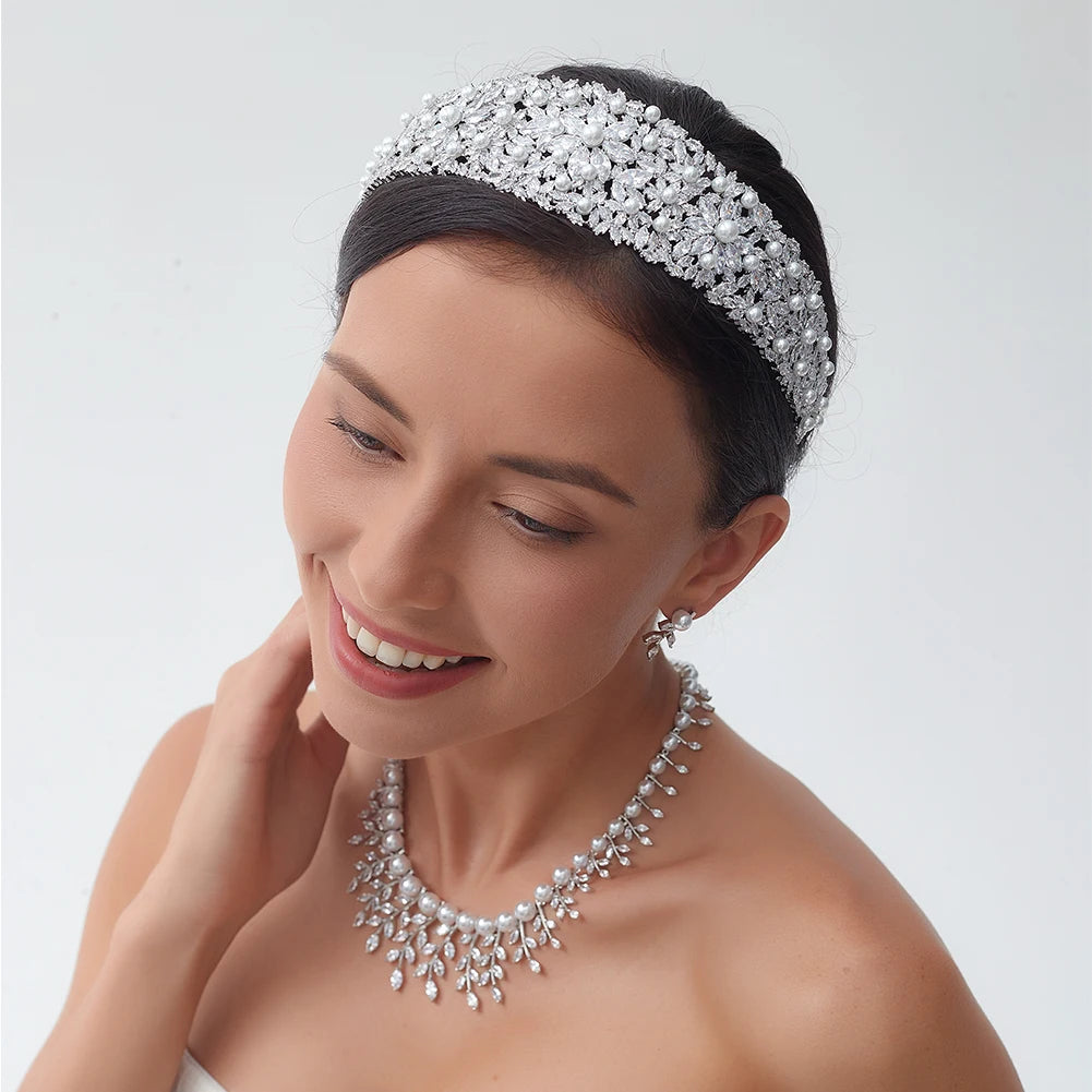 Close-up portrait of a smiling model wearing a luxury bridal pearl headband designed with a thick glamour crystal tiara cluster pattern.
