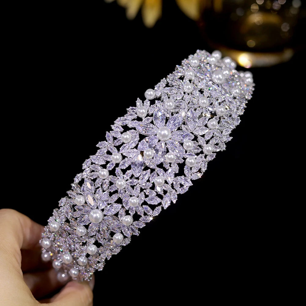 Close-up macro photograph highlighting the intricate floral cluster pattern, pave stone settings, and central pearls of a glamour crystal tiara band.