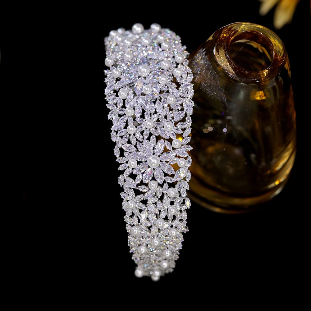 Symmetrical overhead shot of the luxury pearl bridal headband positioned upright next to a decorative brown glass bottle display.