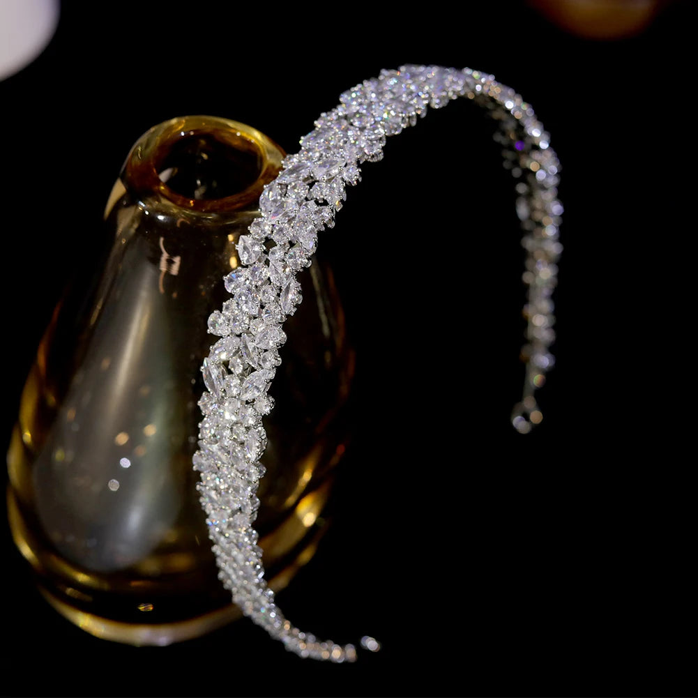 High-angle side view of the premium silver cubic zirconia bridal headband draped gracefully over an amber glass display bottle.