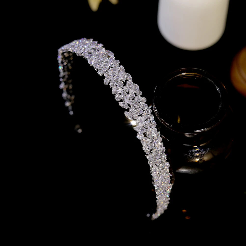 Symmetrical overhead shot of the luxury cubic zirconia wedding headband positioned next to a dark glass display bottle.